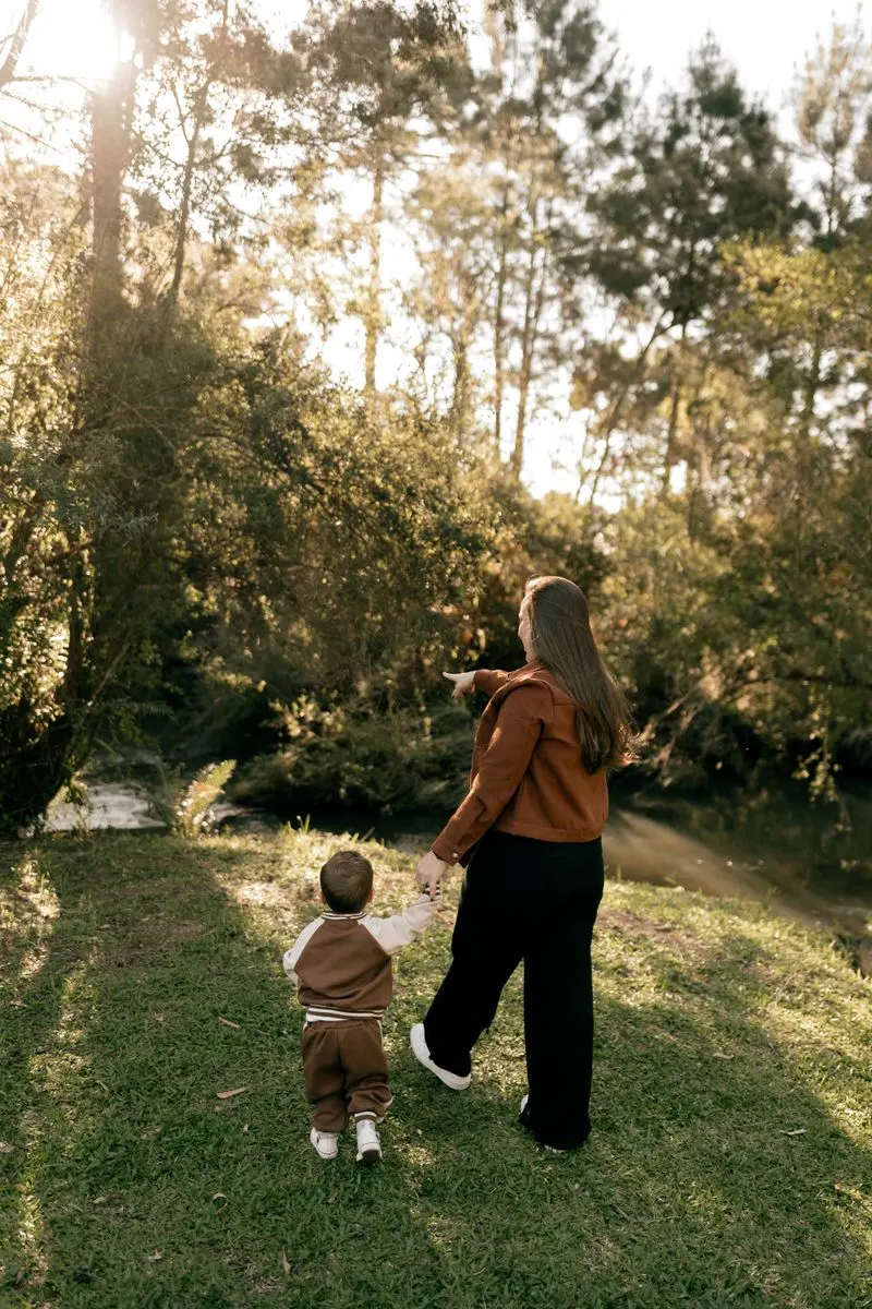 Mãe e filho caminhando de mãos dadas em meio à natureza